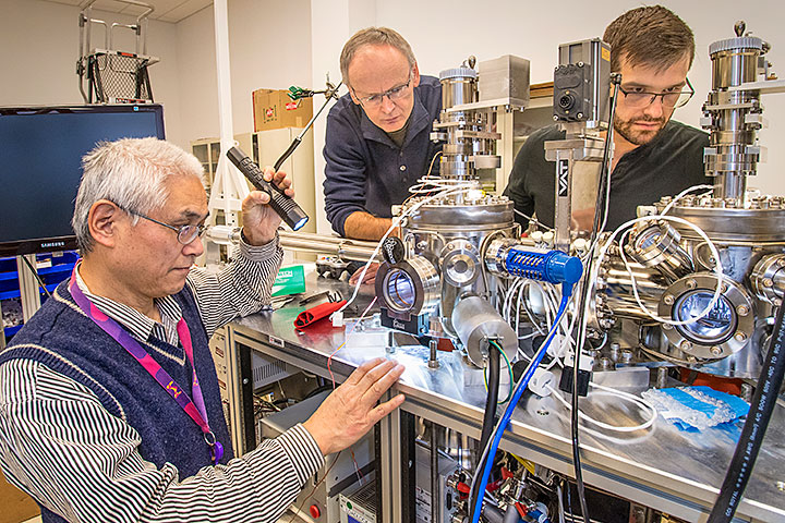 Brookhaven Lab physicists (from left to right) Genda Gu, Tonica Valla, and Ilya Drozdov at OASIS, a new on-site experimental machine for growing and characterizing oxide thin films, such as those of a class of high-temperature superconductors (HTS) known as the cuprates